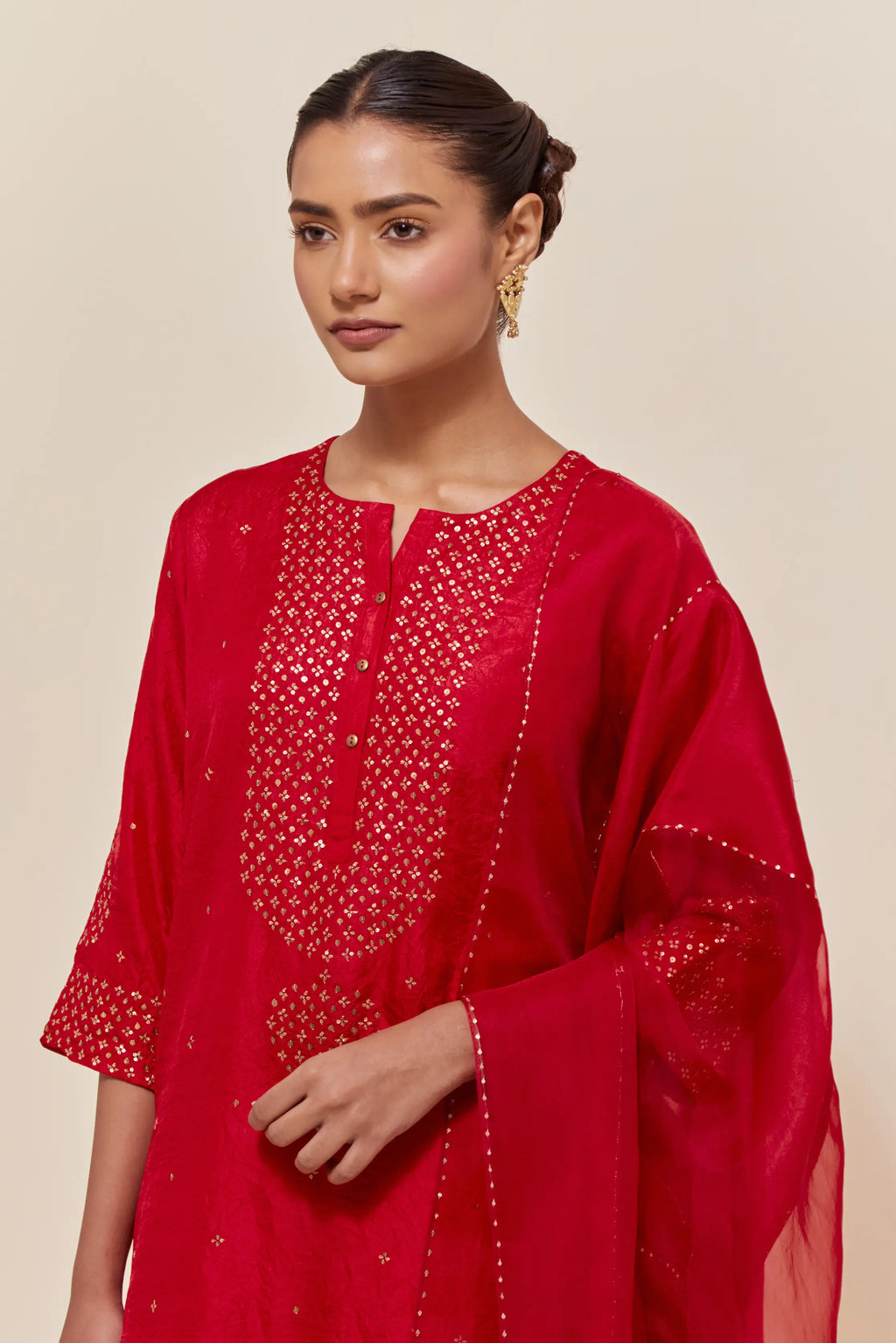 Red silk dupatta with silk organza at the sides, highlighted with hand-embroidered gold sequins work.