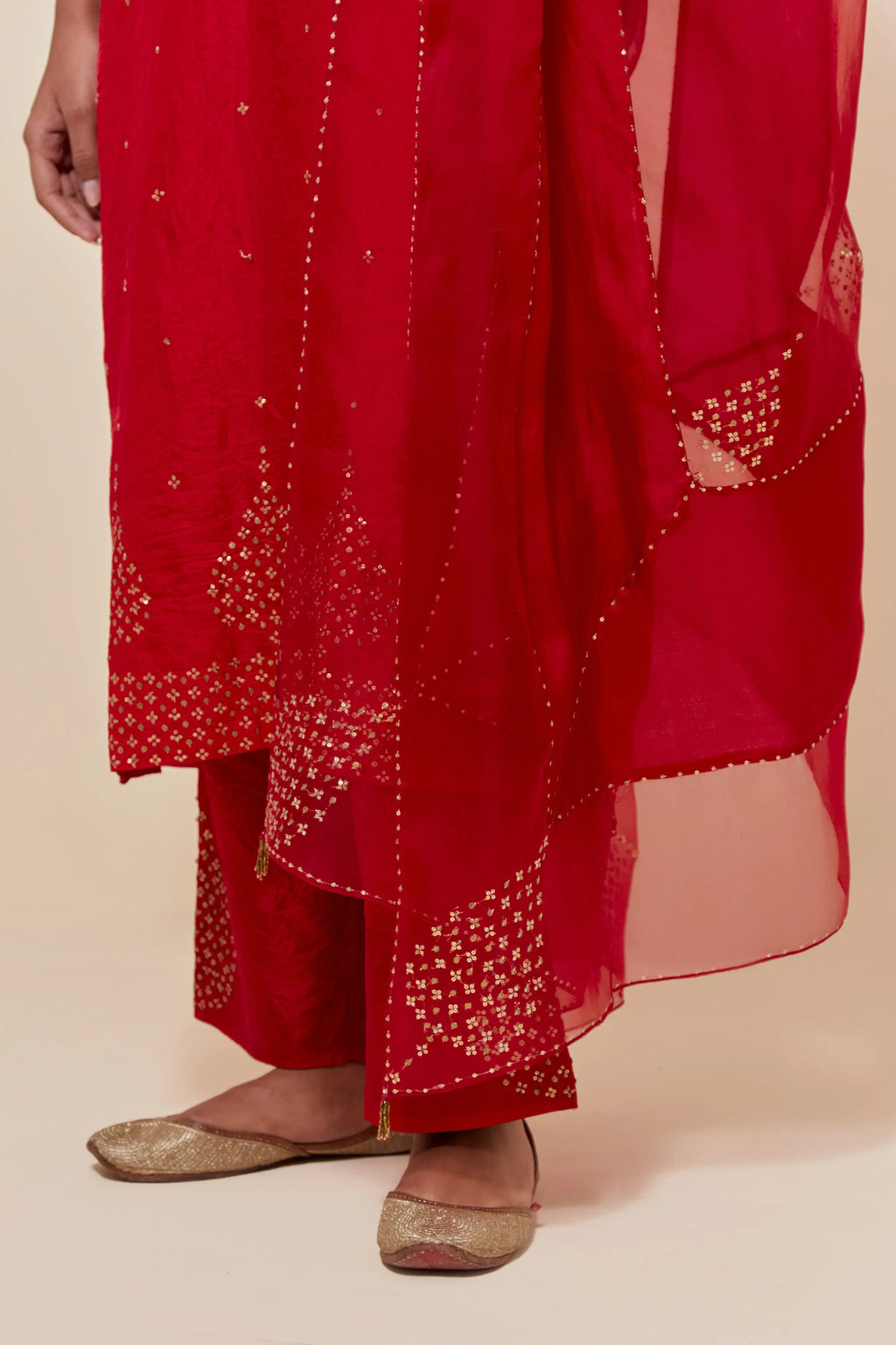 Red silk dupatta with silk organza at the sides, highlighted with hand-embroidered gold sequins work.