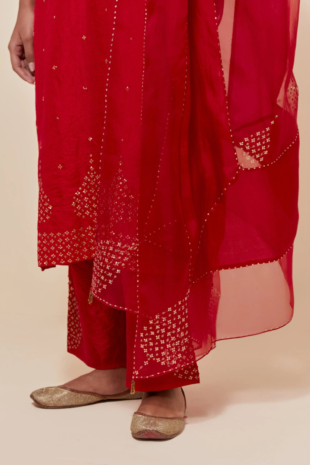 Red silk dupatta with silk organza at the sides, highlighted with hand-embroidered gold sequins work.