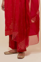 Red silk straight kurta set with hand-embroidered sequins at the neck, borders running along the hem and sleeve edges, and scattered gold sequins embellishments all-over.