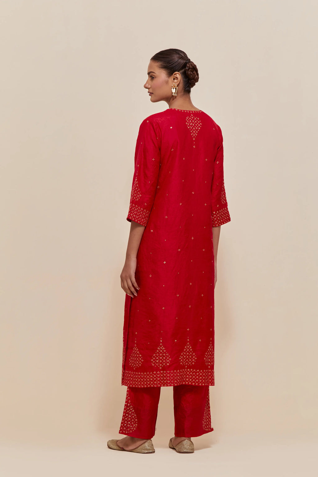 Red silk straight kurta set with hand-embroidered sequins at the neck, borders running along the hem and sleeve edges, and scattered gold sequins embellishments all-over.