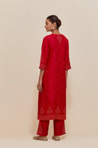 Red silk straight kurta set with hand-embroidered sequins at the neck, borders running along the hem and sleeve edges, and scattered gold sequins embellishments all-over.