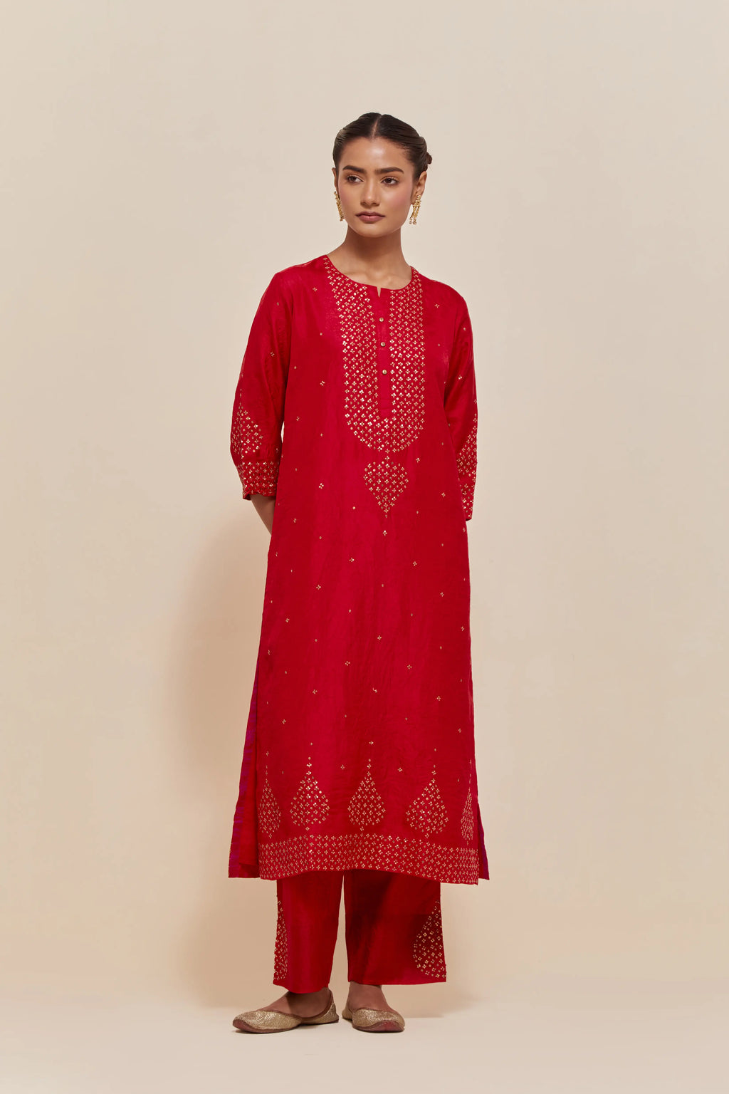 Red silk straight kurta set with hand-embroidered sequins at the neck, borders running along the hem and sleeve edges, and scattered gold sequins embellishments all-over.