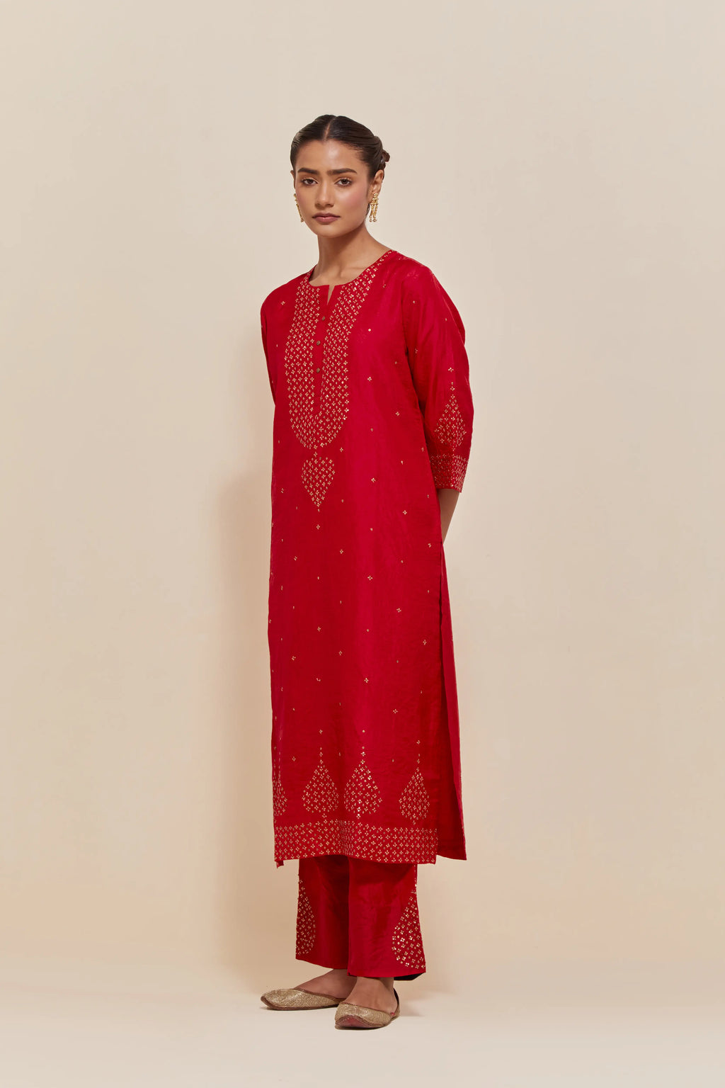 Red silk straight kurta set with hand-embroidered sequins at the neck, borders running along the hem and sleeve edges, and scattered gold sequins embellishments all-over.
