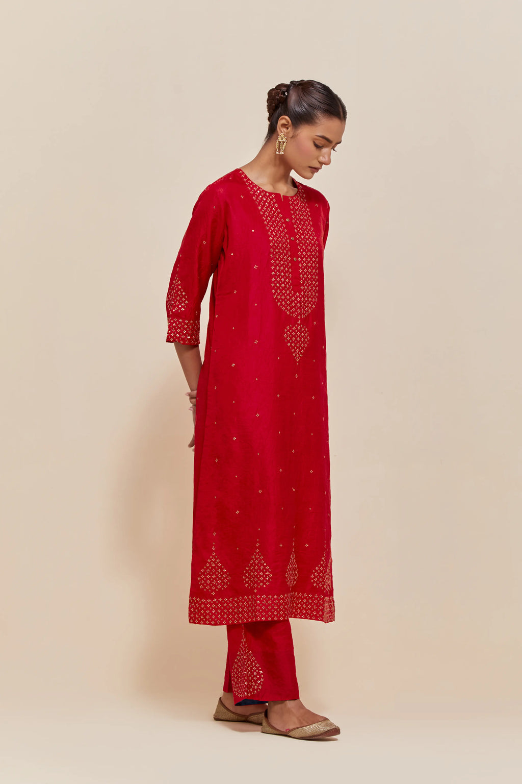 Red silk straight kurta set with hand-embroidered sequins at the neck, borders running along the hem and sleeve edges, and scattered gold sequins embellishments all-over.