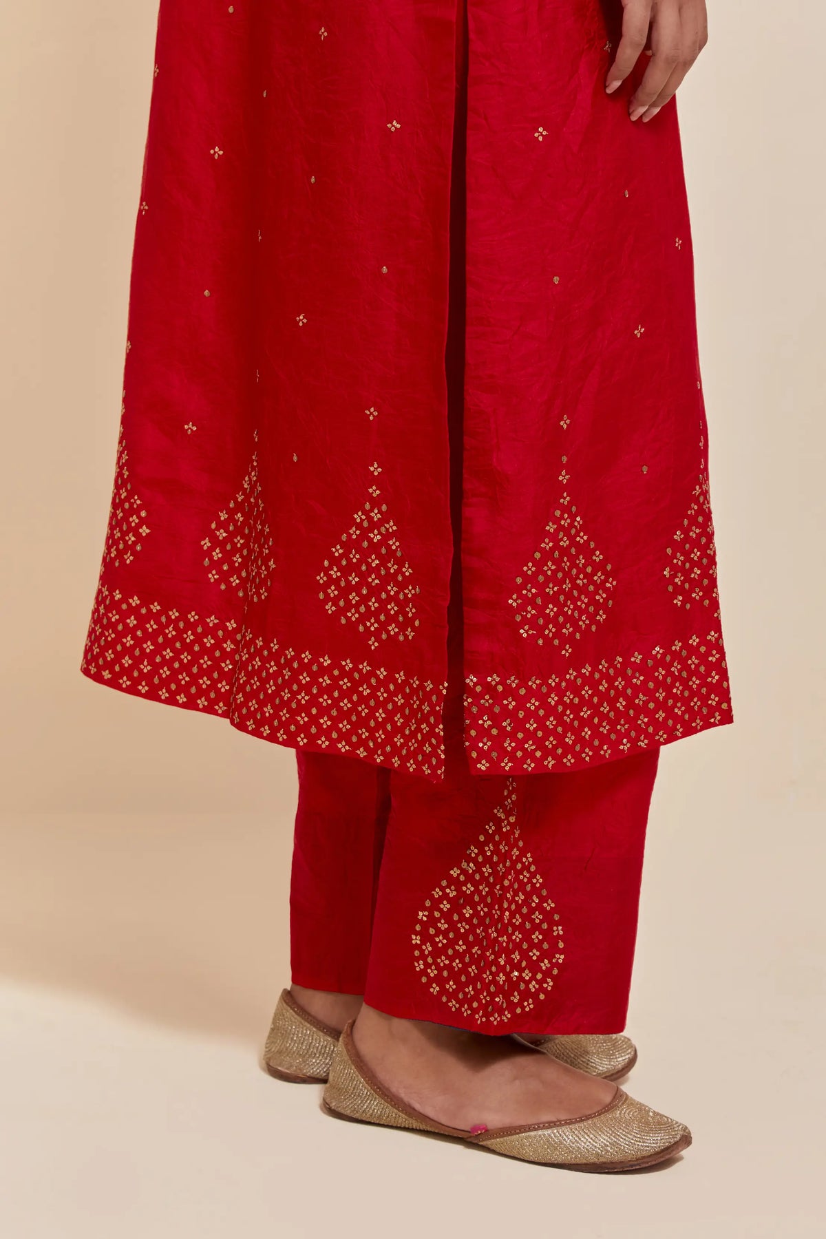 Red silk straight kurta set with hand-embroidered sequins at the neck, borders running along the hem and sleeve edges, and scattered gold sequins embellishments all-over.