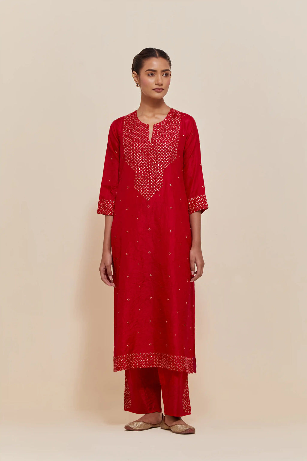 Red silk straight kurta set with hand-embroidered sequins at the neck, hem and sleeves, highlighted with scattered gold sequins embellishments all-over.
