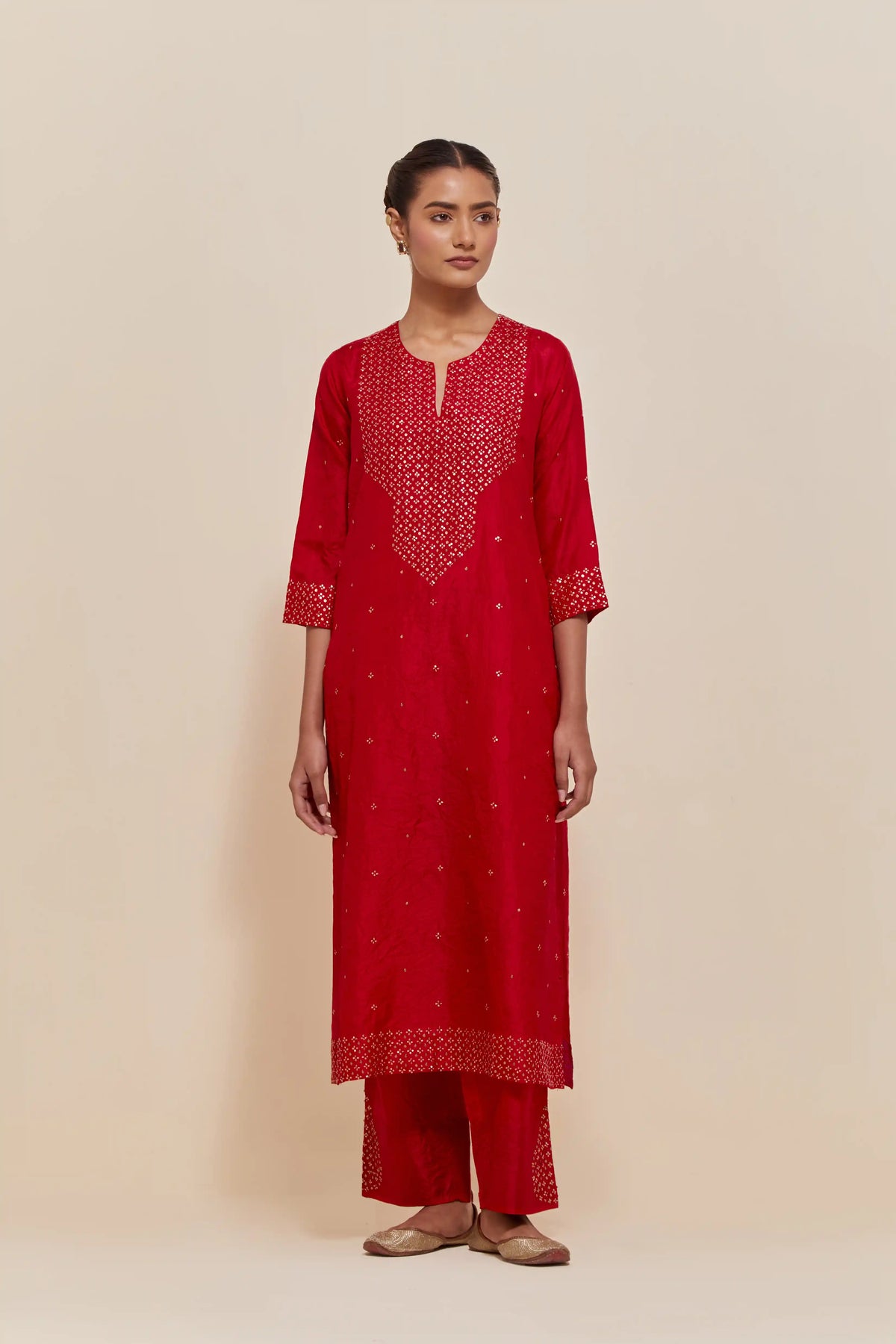Red silk straight kurta set with hand-embroidered sequins at the neck, hem and sleeves, highlighted with scattered gold sequins embellishments all-over.
