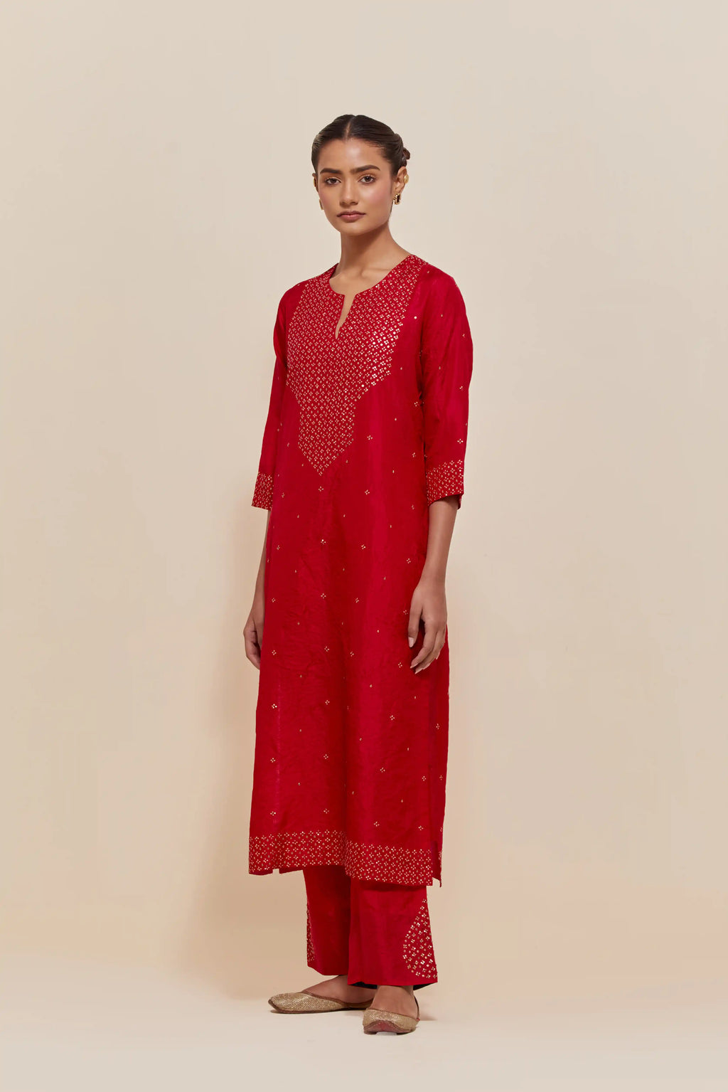 Red silk straight kurta set with hand-embroidered sequins at the neck, hem and sleeves, highlighted with scattered gold sequins embellishments all-over.