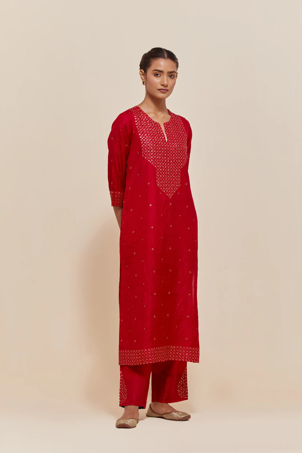 Red silk straight kurta set with hand-embroidered sequins at the neck, hem and sleeves, highlighted with scattered gold sequins embellishments all-over.