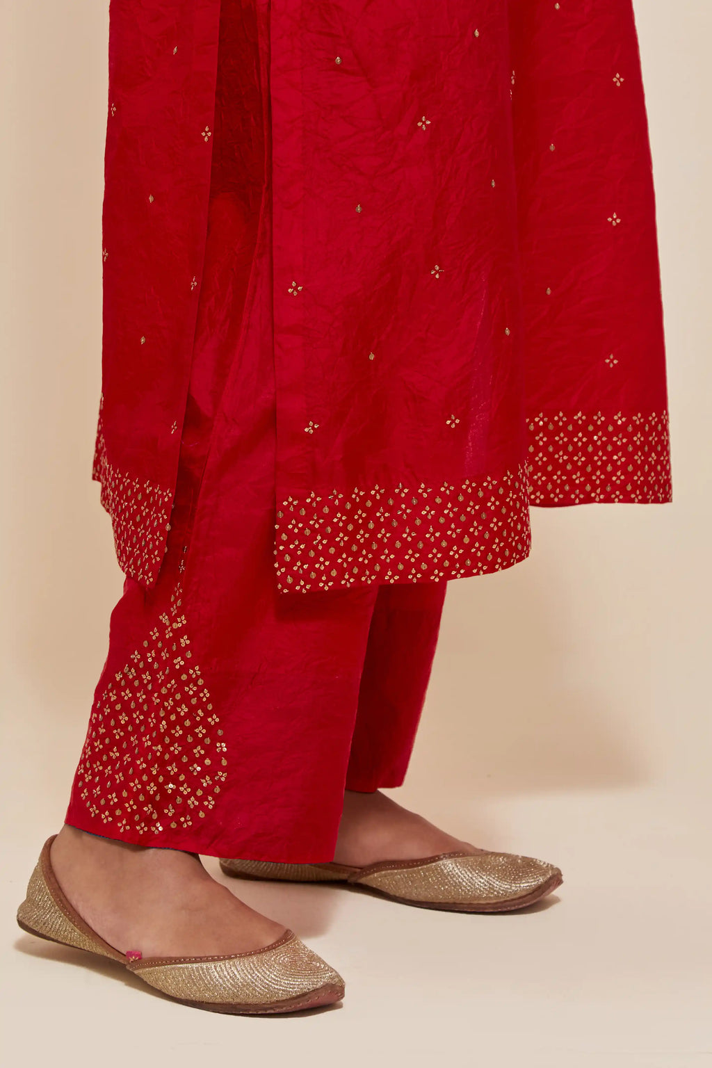 Red silk straight kurta set with hand-embroidered sequins at the neck, hem and sleeves, highlighted with scattered gold sequins embellishments all-over.