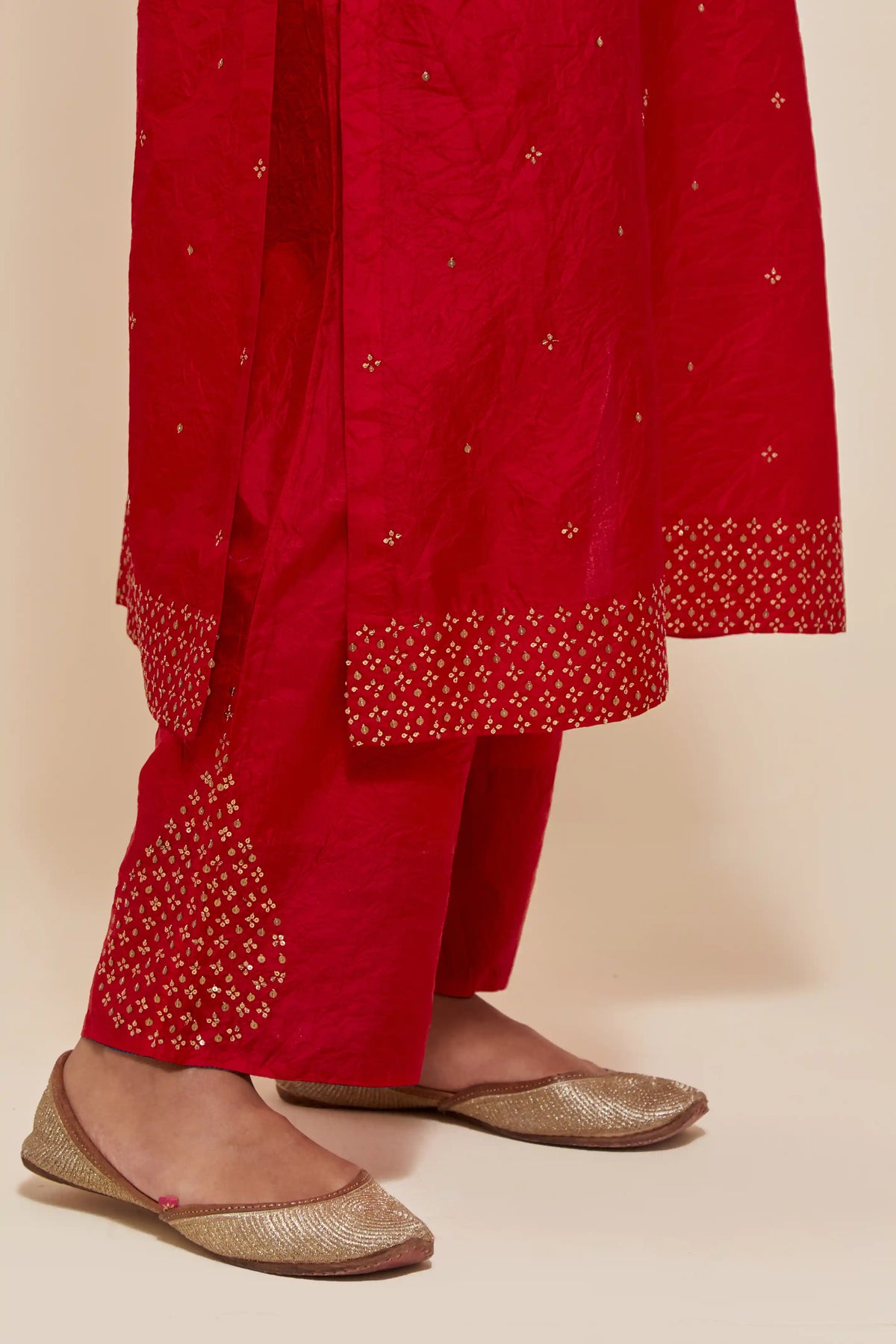 Red silk straight kurta set with hand-embroidered sequins at the neck, hem and sleeves, highlighted with scattered gold sequins embellishments all-over.