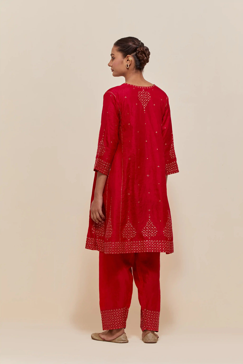 Red silk short kalidar kurta set, with hand embroidered sequins at neck, hem and sleeve edges, highlighted with scattered gold sequins embellishments all-over.