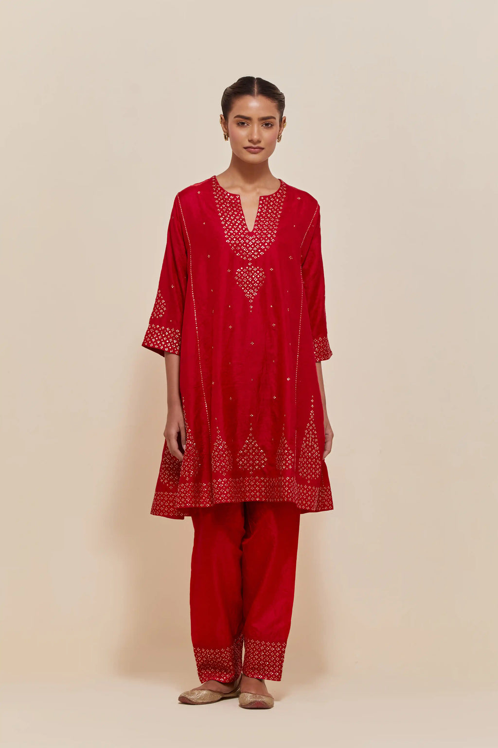 Red silk short kalidar kurta set, with hand embroidered sequins at neck, hem and sleeve edges, highlighted with scattered gold sequins embellishments all-over.