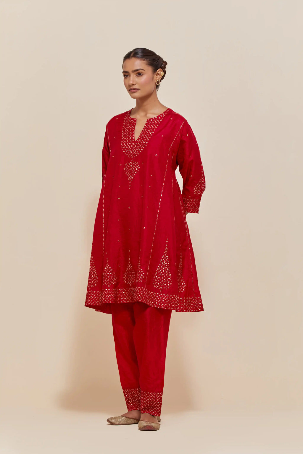 Red silk short kalidar kurta set, with hand embroidered sequins at neck, hem and sleeve edges, highlighted with scattered gold sequins embellishments all-over.