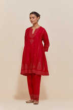 Red silk short kalidar kurta set, with hand embroidered sequins at neck, hem and sleeve edges, highlighted with scattered gold sequins embellishments all-over.