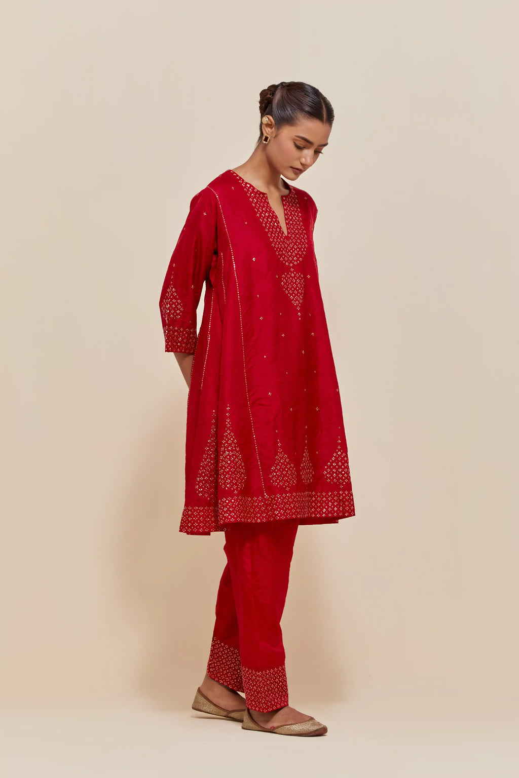 Red silk short kalidar kurta set, with hand embroidered sequins at neck, hem and sleeve edges, highlighted with scattered gold sequins embellishments all-over.
