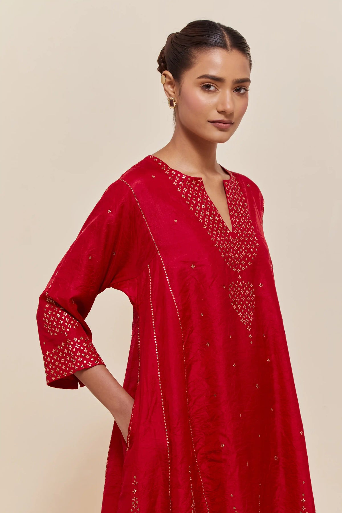 Red silk short kalidar kurta set, with hand embroidered sequins at neck, hem and sleeve edges, highlighted with scattered gold sequins embellishments all-over.