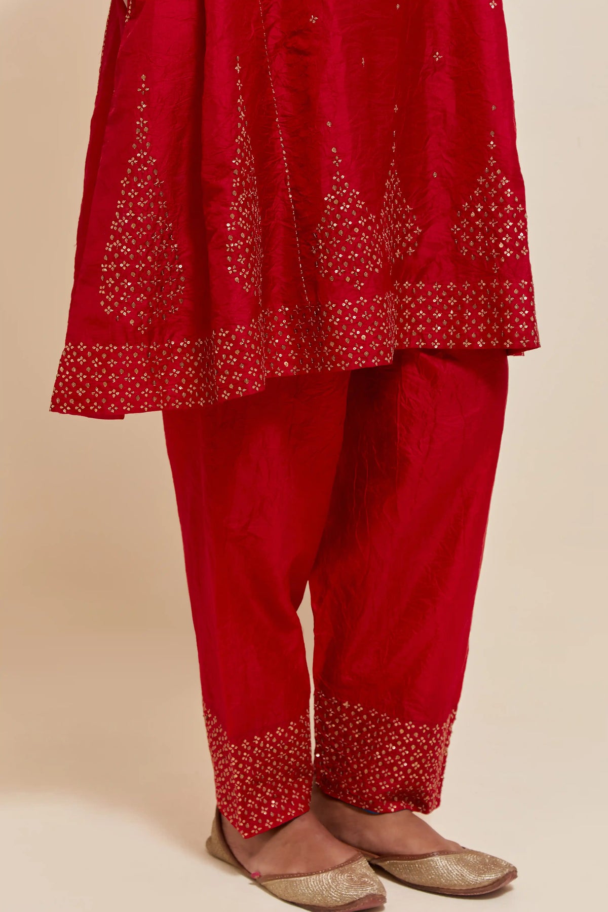 Red silk short kalidar kurta set, with hand embroidered sequins at neck, hem and sleeve edges, highlighted with scattered gold sequins embellishments all-over.
