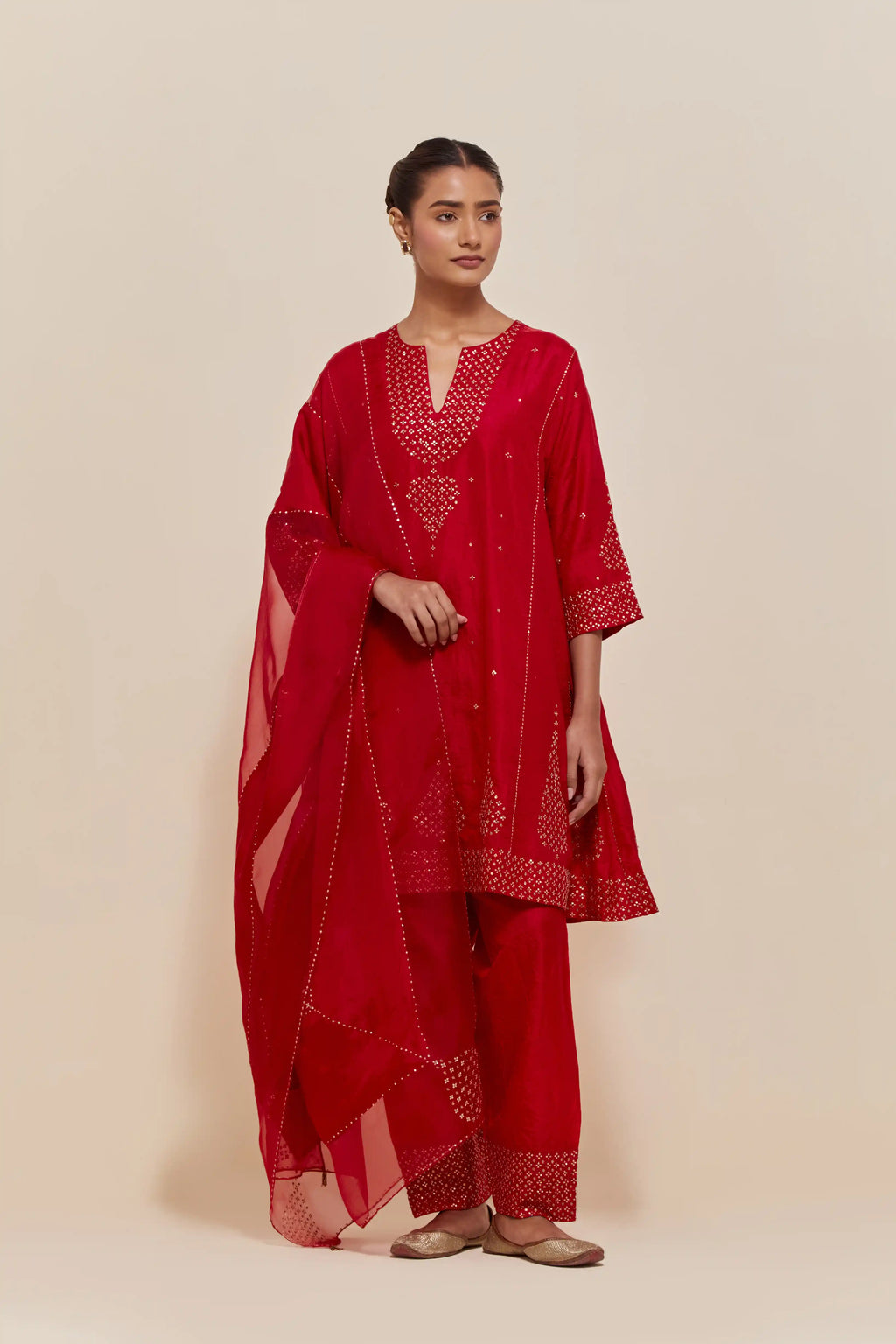 Red silk short kalidar kurta set, with hand embroidered sequins at neck, hem and sleeve edges, highlighted with scattered gold sequins embellishments all-over.