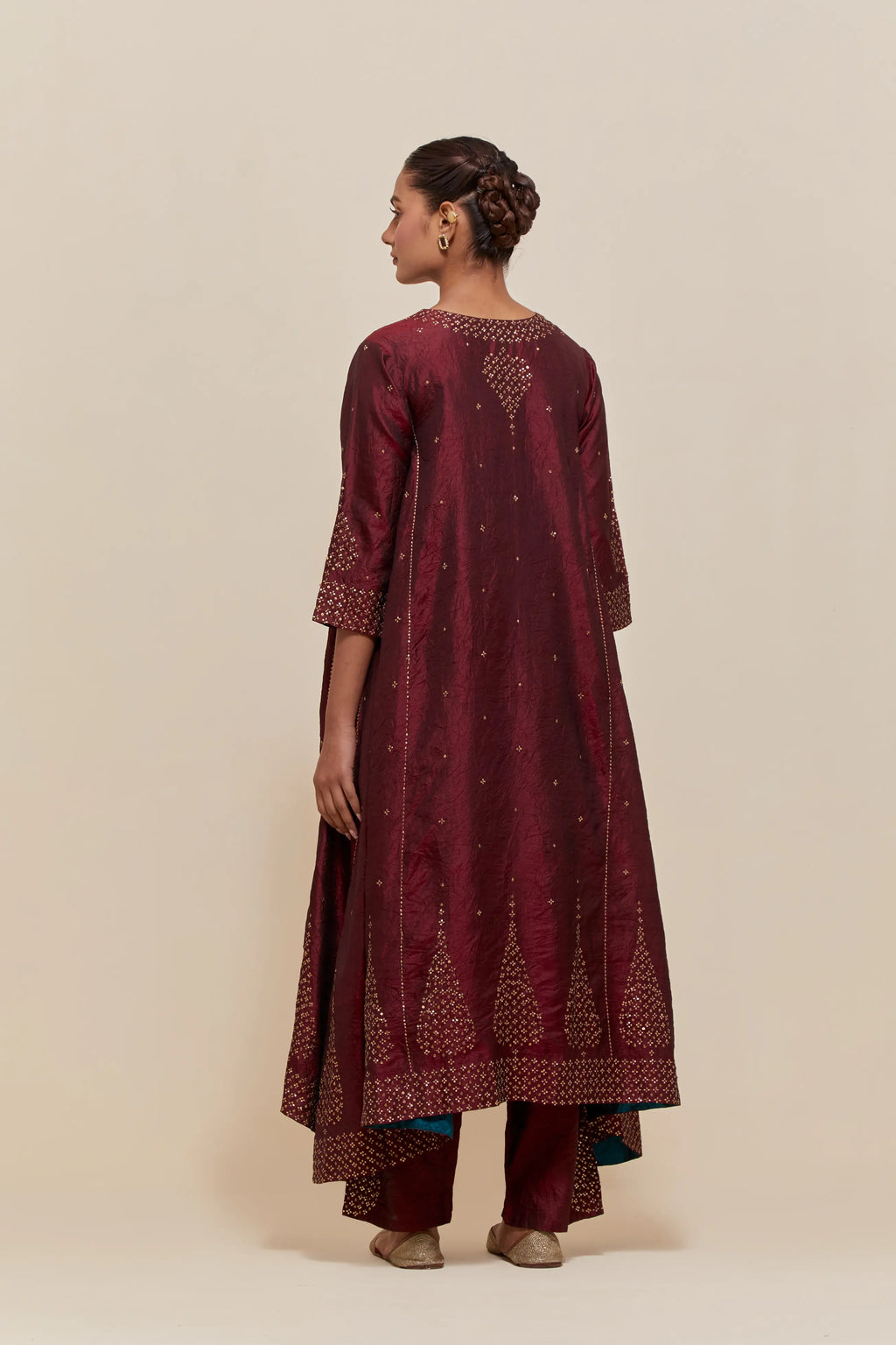 Maroon silk kurta set with asymmetric hem and hand-embroidered leaf motifs with delicate sequins work at the neck, sleeves, and hem, with sequins border running along the edges.