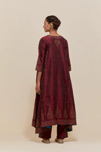 Maroon silk kurta set with asymmetric hem and hand-embroidered leaf motifs with delicate sequins work at the neck, sleeves, and hem, with sequins border running along the edges.