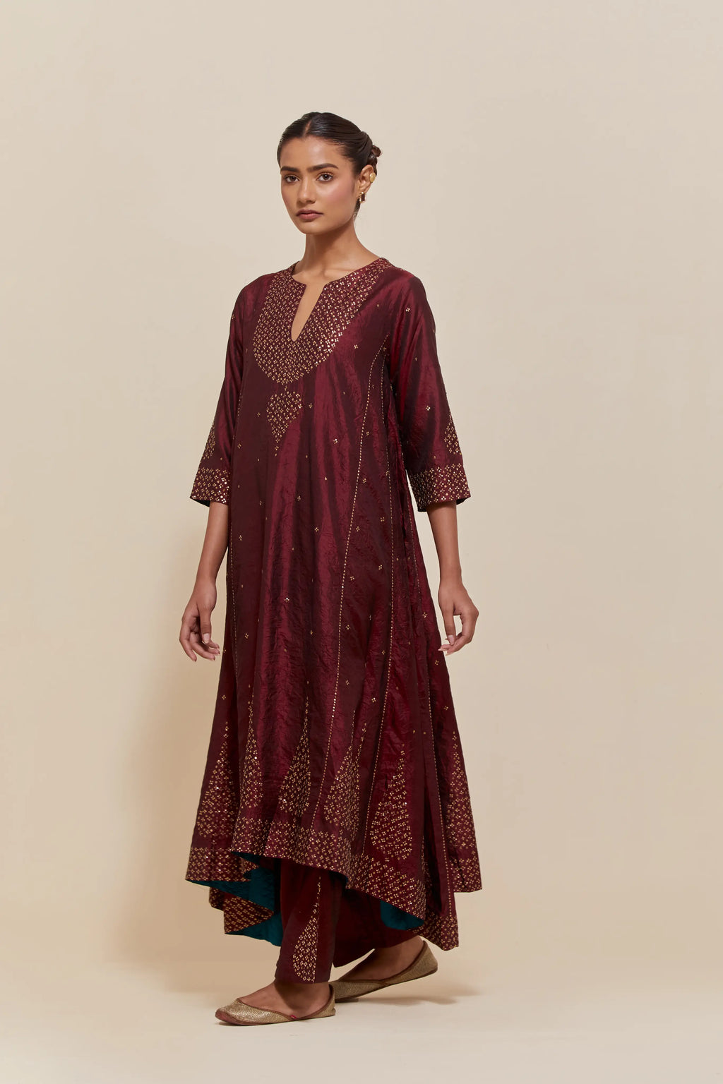 Maroon silk kurta set with asymmetric hem and hand-embroidered leaf motifs with delicate sequins work at the neck, sleeves, and hem, with sequins border running along the edges.