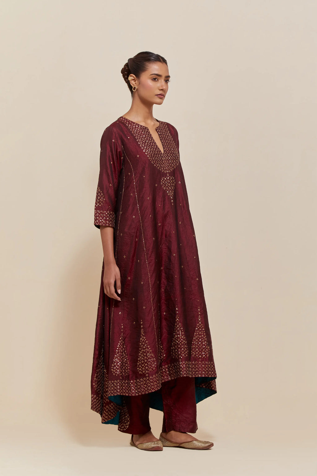 Maroon silk kurta set with asymmetric hem and hand-embroidered leaf motifs with delicate sequins work at the neck, sleeves, and hem, with sequins border running along the edges.