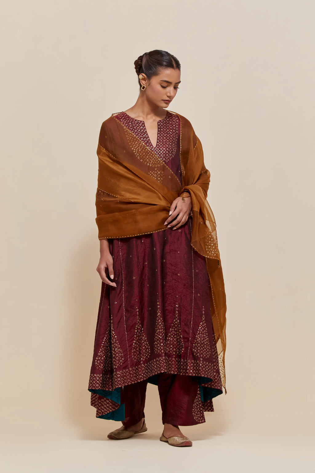 Maroon silk kurta set with asymmetric hem and hand-embroidered leaf motifs with delicate sequins work at the neck, sleeves, and hem, with sequins border running along the edges.