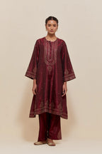 Maroon silk A-line short kurta set with hand-embroidered sequins at the neck, borders running along the hem and sleeve edges, and scattered gold sequin embellishments all-over.
