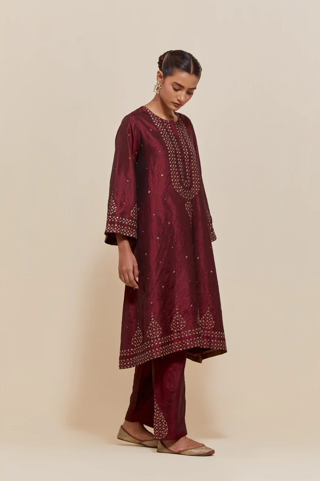 Maroon silk A-line short kurta set with hand-embroidered sequins at the neck, borders running along the hem and sleeve edges, and scattered gold sequin embellishments all-over.
