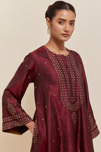 Maroon silk A-line short kurta set with hand-embroidered sequins at the neck, borders running along the hem and sleeve edges, and scattered gold sequin embellishments all-over.