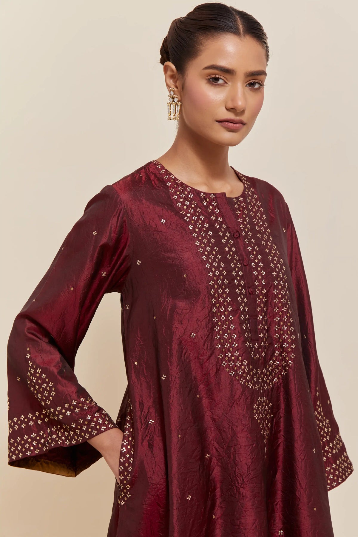 Maroon silk A-line short kurta set with hand-embroidered sequins at the neck, borders running along the hem and sleeve edges, and scattered gold sequin embellishments all-over.