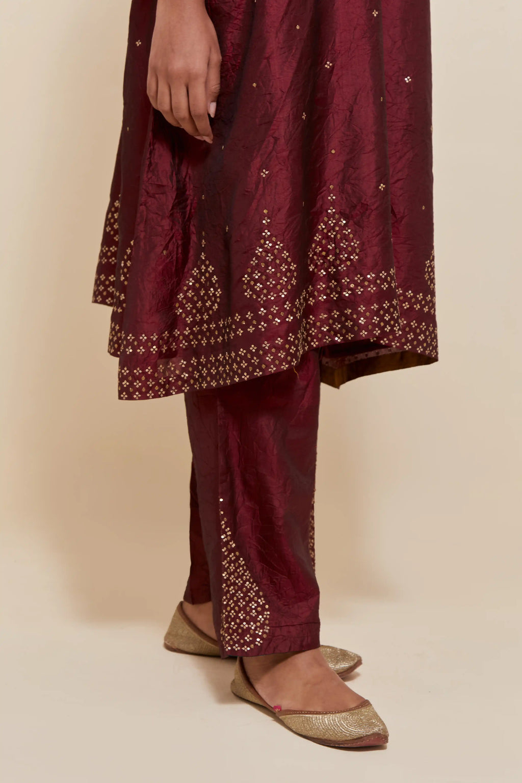 Maroon silk A-line short kurta set with hand-embroidered sequins at the neck, borders running along the hem and sleeve edges, and scattered gold sequin embellishments all-over.