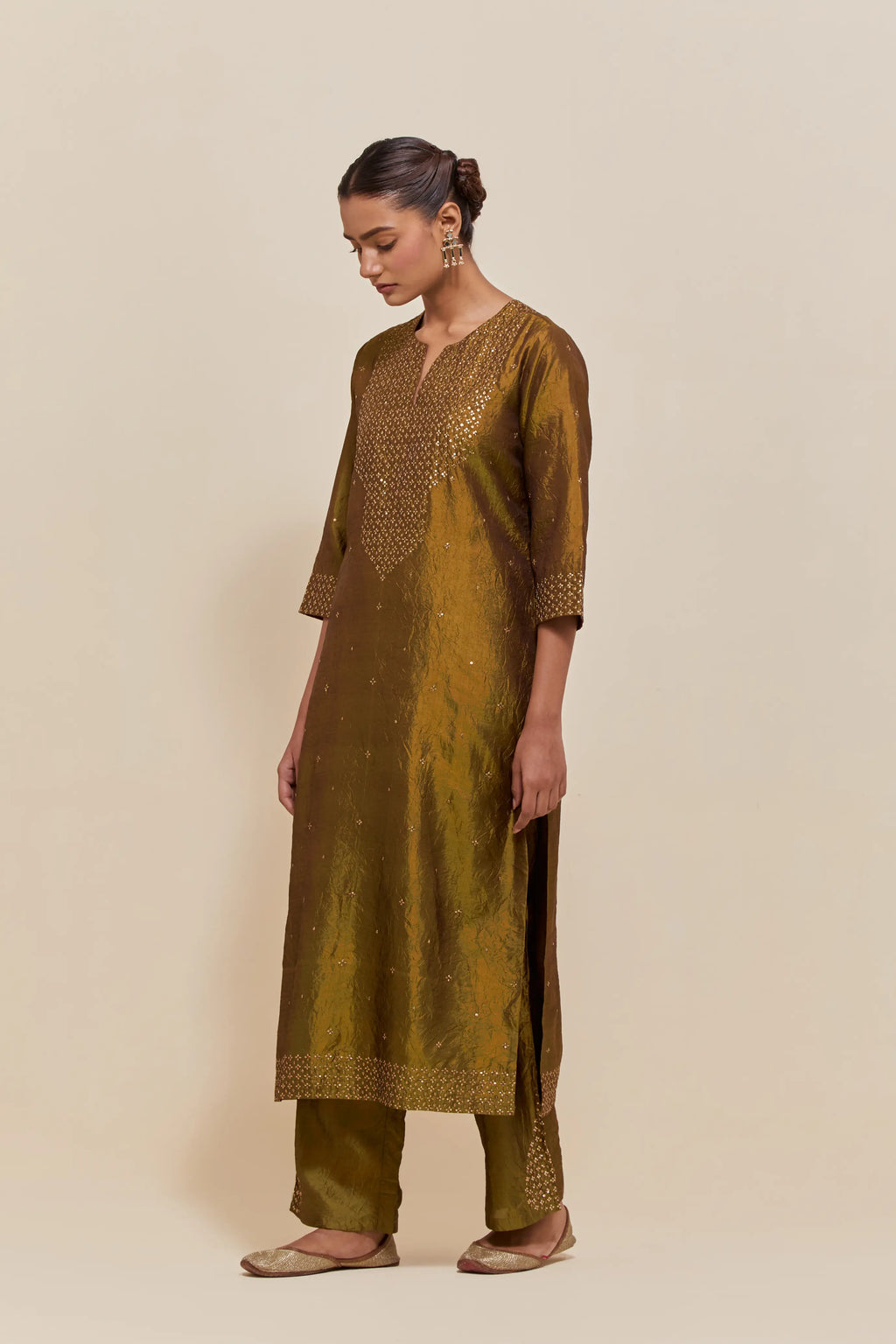 Olive silk straight kurta set with hand-embroidered sequins at the neck, hem and sleeves, highlighted with scattered gold sequins embellishments all-over.
