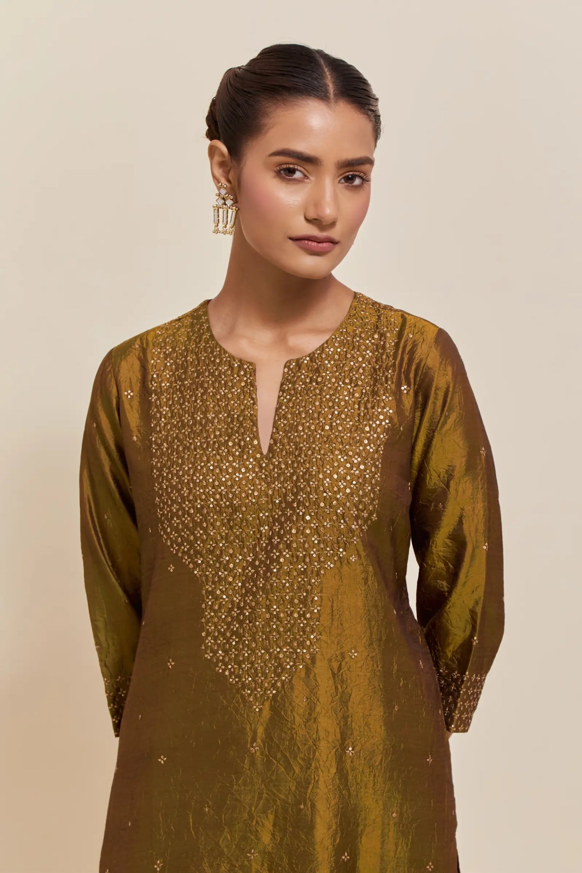 Olive silk straight kurta set with hand-embroidered sequins at the neck, hem and sleeves, highlighted with scattered gold sequins embellishments all-over.