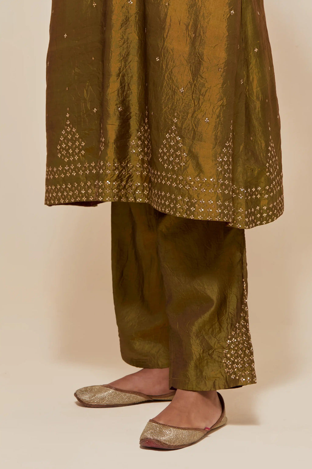 Olive silk A-line short kurta set with hand-embroidered sequins at the neck, borders running along the hem and sleeve edges, and scattered gold sequin embellishments all-over.