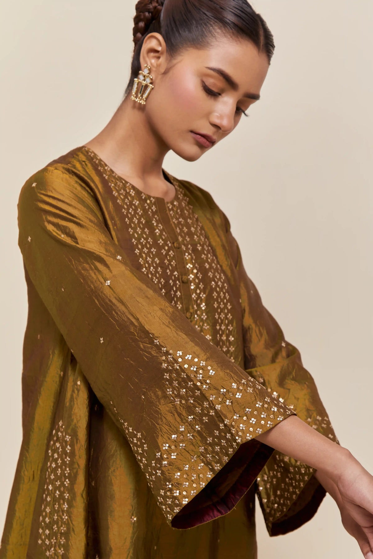 Olive silk A-line short kurta set with hand-embroidered sequins at the neck, borders running along the hem and sleeve edges, and scattered gold sequin embellishments all-over.