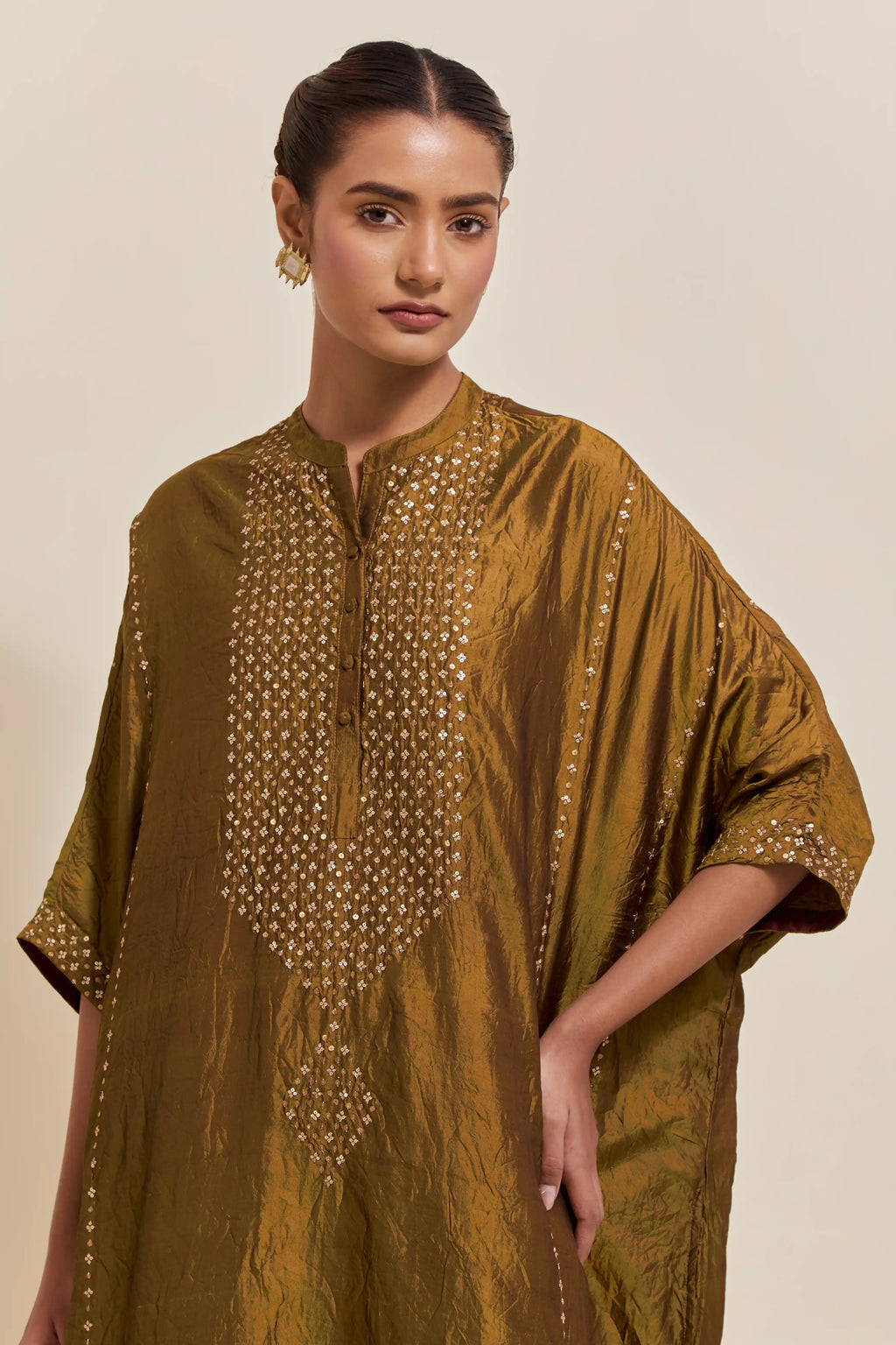 Olive silk long kaftan with hand-embroidered sequins at the neck and diamond motifs along the sides, paired with olive Silk pants with hand embroidered leaf motifs with delicate sequins work at hem.