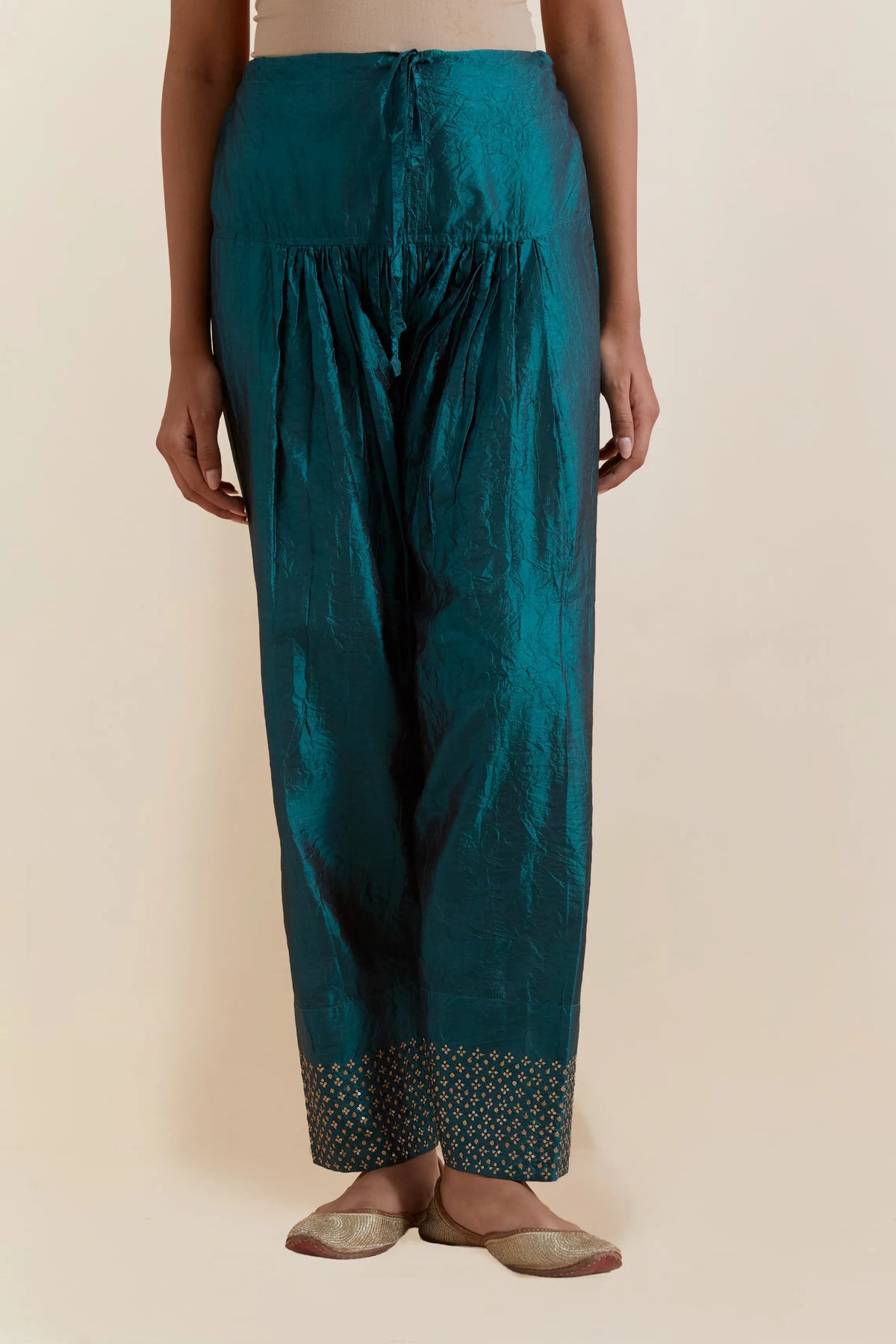 Teal green silk salwar with hand-embroidered gold sequin work in a broad border at the hem.