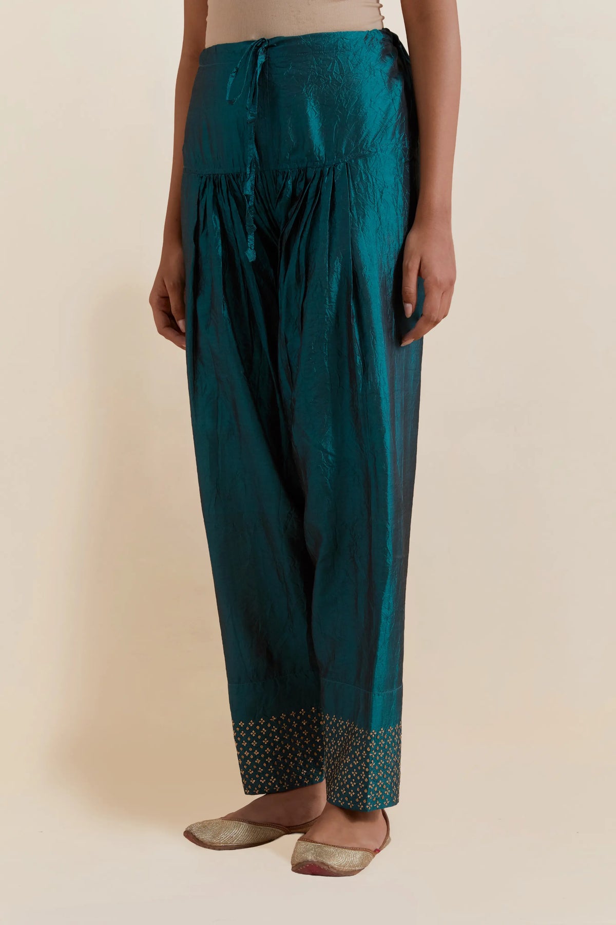 Teal green silk salwar with hand-embroidered gold sequin work in a broad border at the hem.