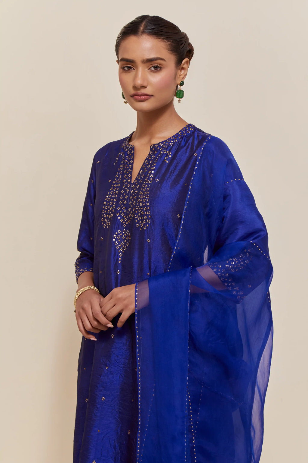 Blue silk straight kurta set with hand-embroidered paisley motifs with delicate gold sequins work at neck, hem, and sleeves, with narrow borders along the edges.
