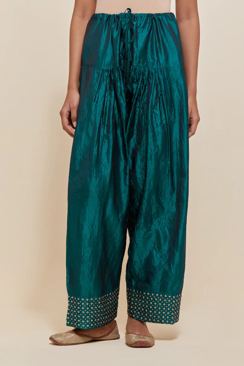Teal green silk farshi salwar with hand-embroidered gold sequins work in a broad border at the hem.