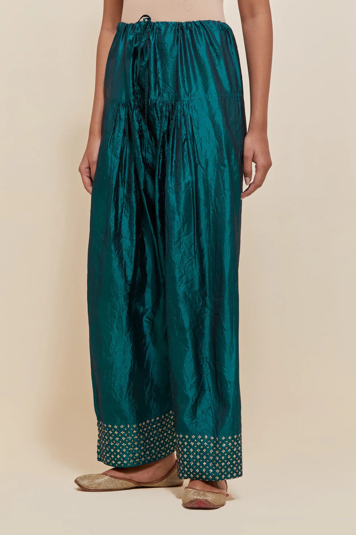 Teal green silk farshi salwar with hand-embroidered gold sequins work in a broad border at the hem.