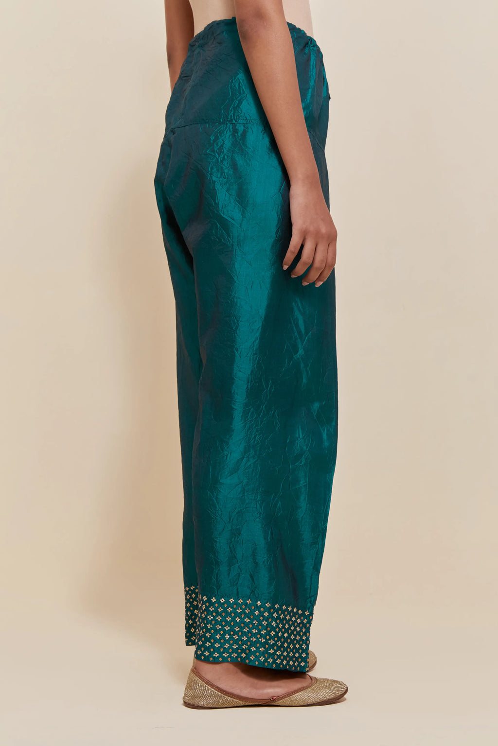 Teal green silk farshi salwar with hand-embroidered gold sequins work in a broad border at the hem.