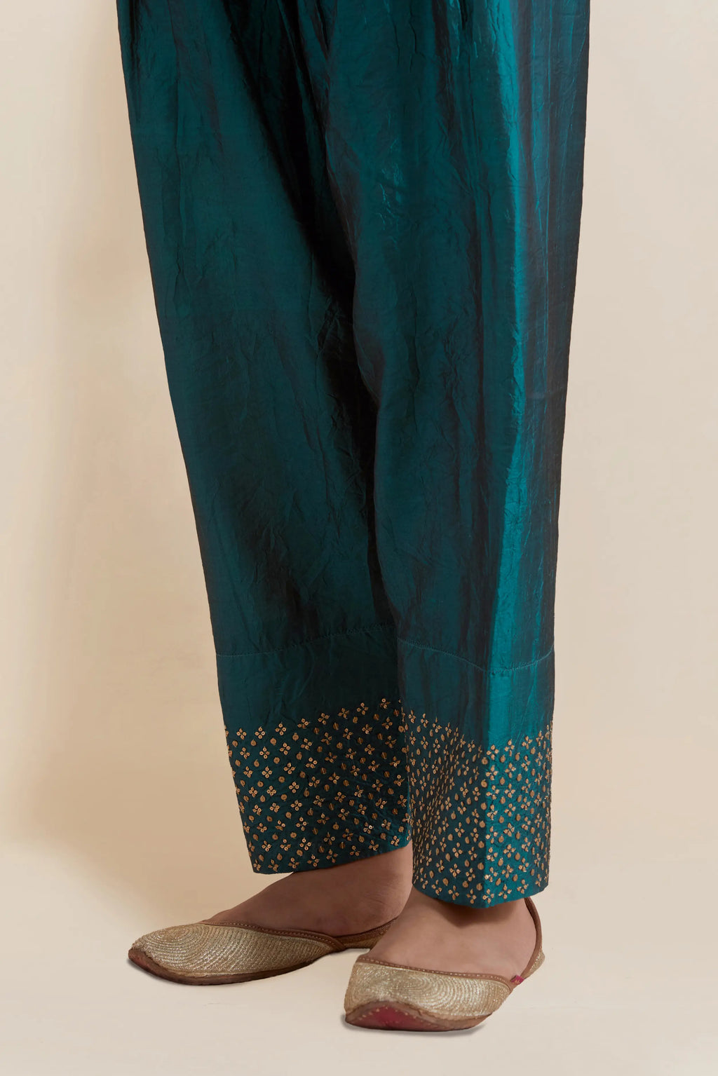 Teal green silk salwar with hand-embroidered gold sequin work in a broad border at the hem.