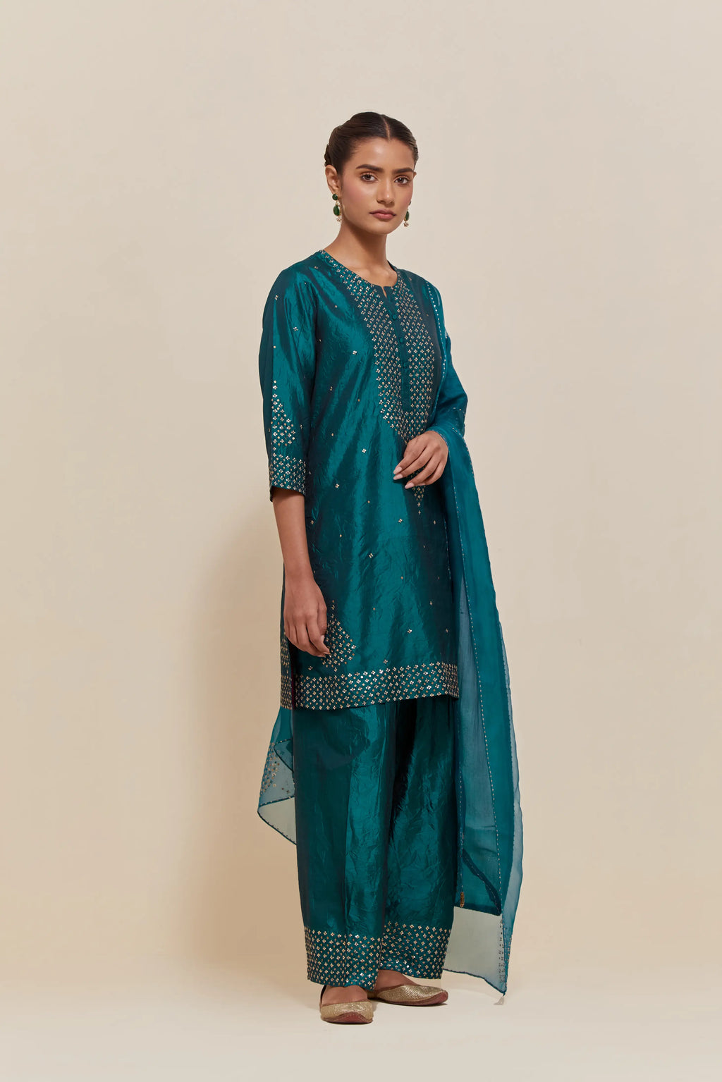 Teal green silk straight short kurta set with hand-embroidered sequins at the neck, borders running along the hem and sleeve edges, and scattered gold sequins embellishments all-over.