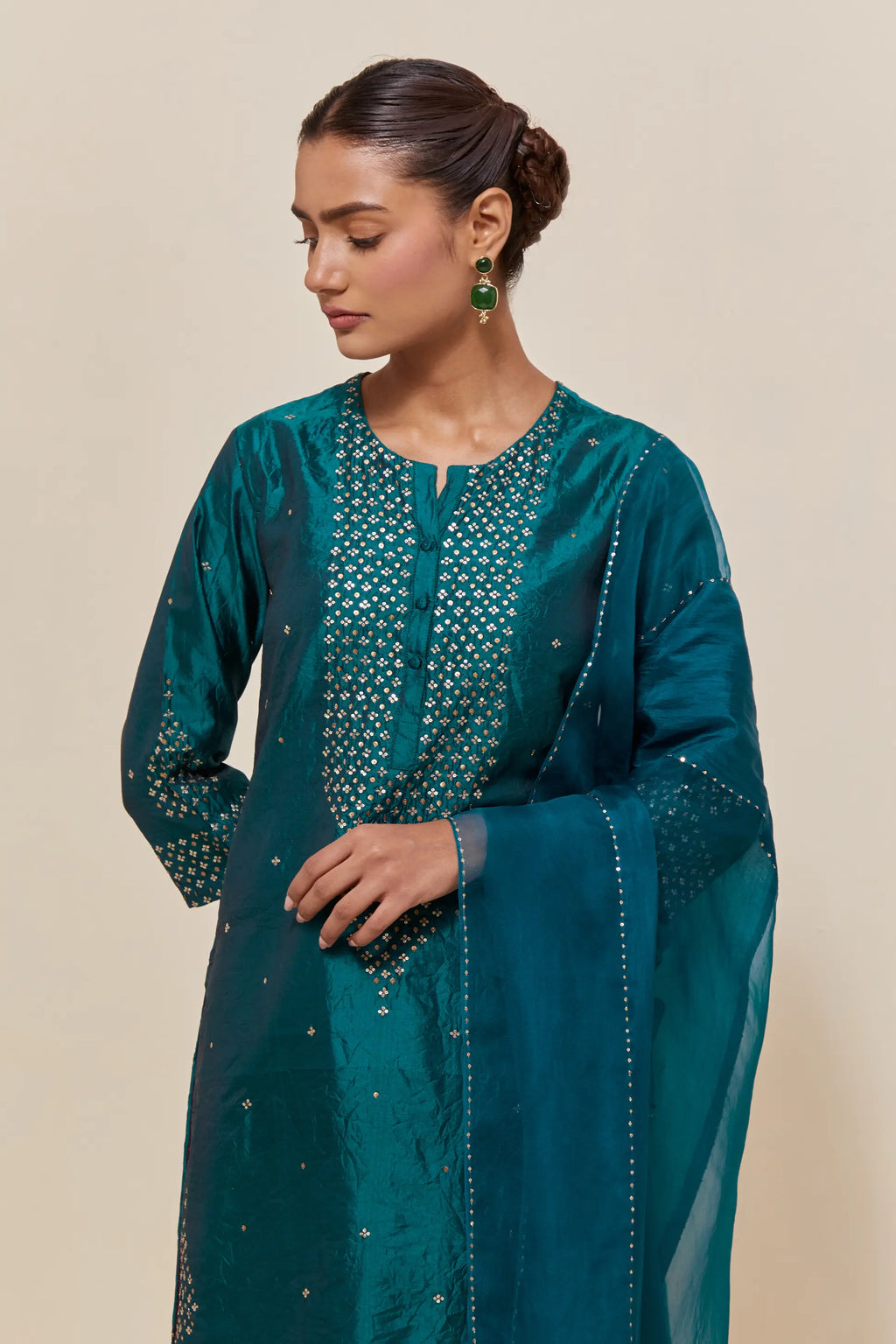 Teal green silk straight short kurta set with hand-embroidered sequins at the neck, borders running along the hem and sleeve edges, and scattered gold sequins embellishments all-over.