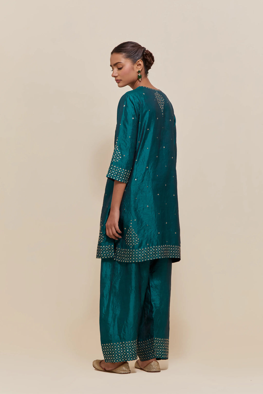 Teal green silk straight short kurta set with hand-embroidered sequins at the neck, borders running along the hem and sleeve edges, and scattered gold sequins embellishments all-over.