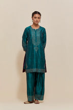 Teal green silk straight short kurta set with hand-embroidered sequins at the neck, borders running along the hem and sleeve edges, and scattered gold sequins embellishments all-over.